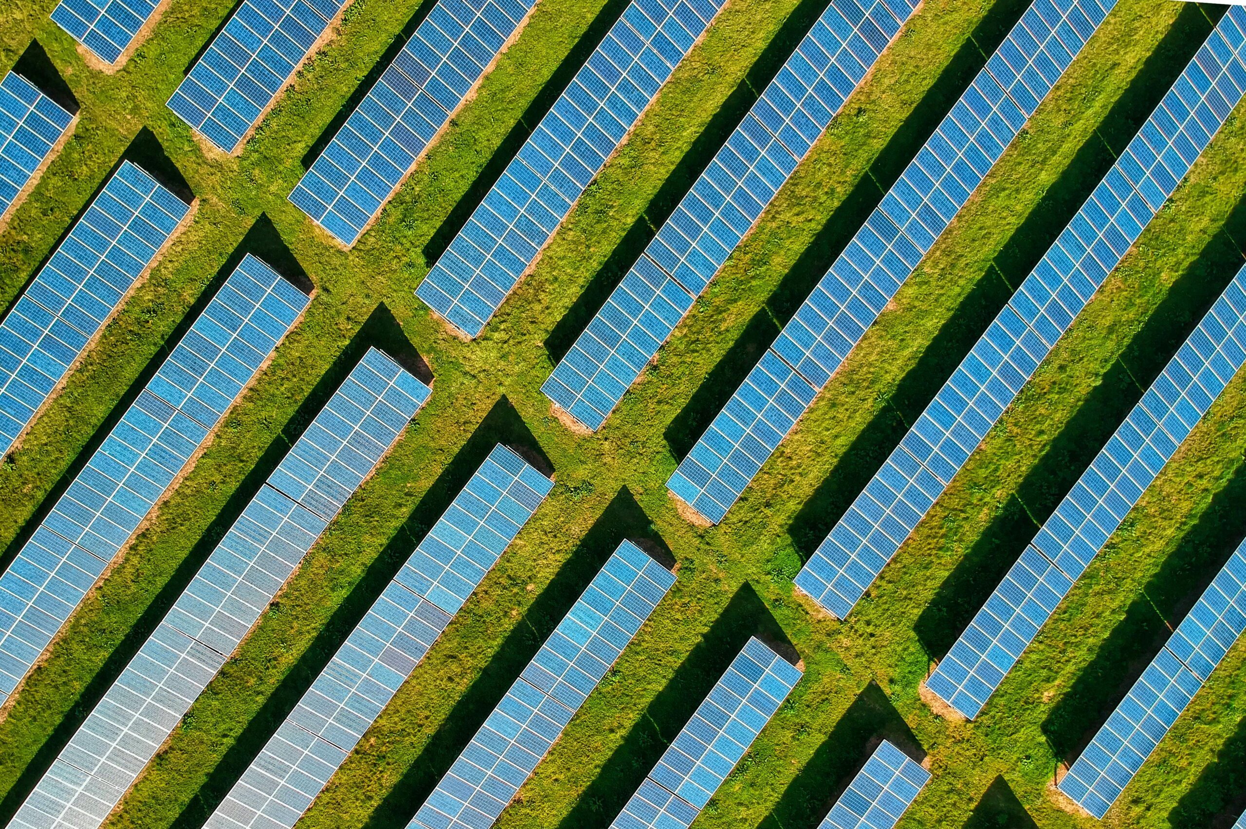 High-angle aerial shot of solar panels in a lush green field, located in Rockbeare, UK.